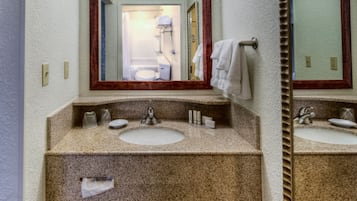 Un baño con encimera de granito, dos lavabos, un espejo y un perchero para toallas.