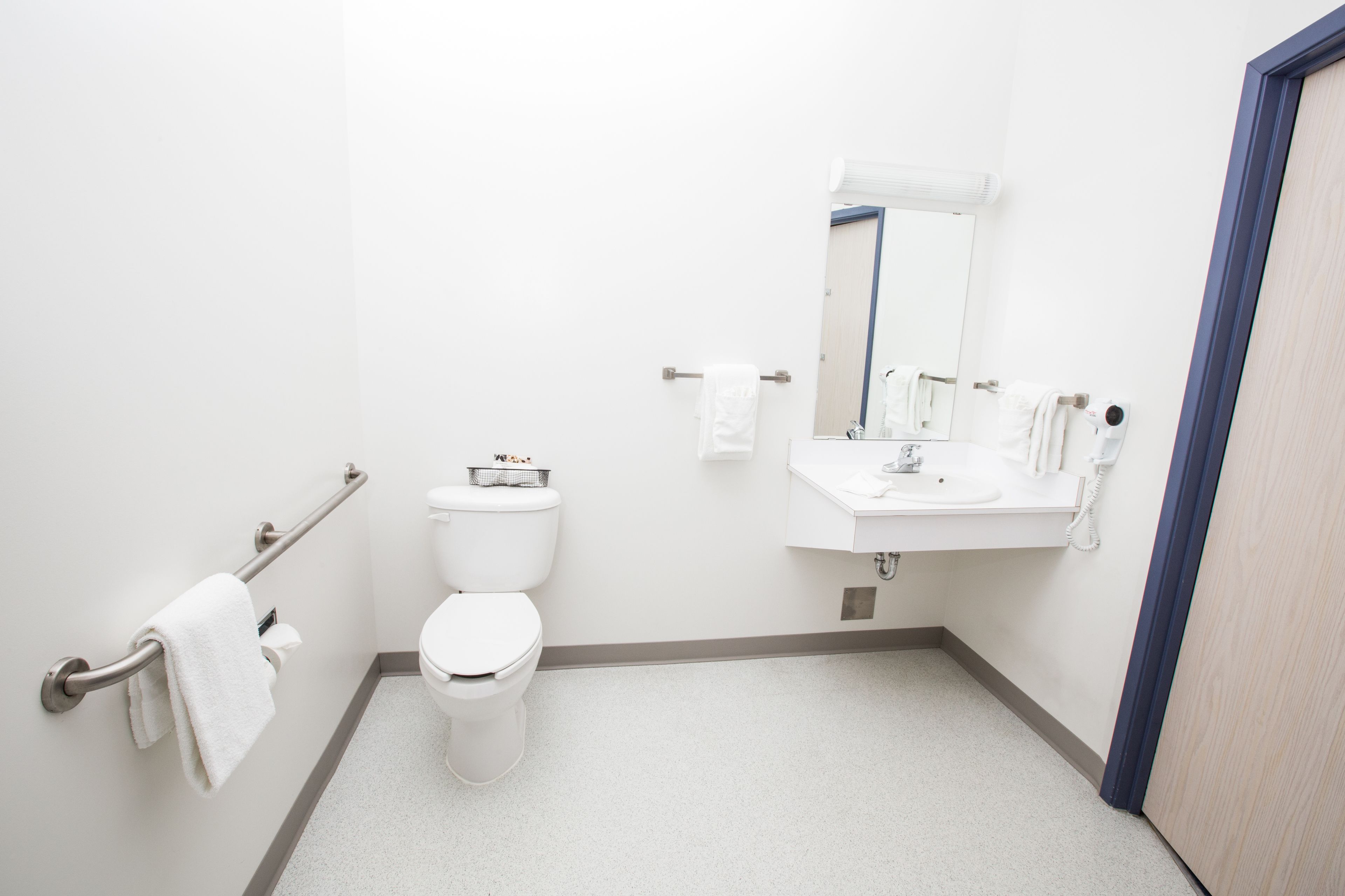 A small, clean bathroom with a toilet, sink, and mirror.