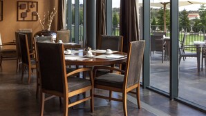 A dining area with a round table, chairs, and a vase with branches.