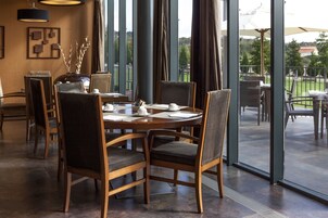 A dining area with a round table, chairs, and a vase with branches.