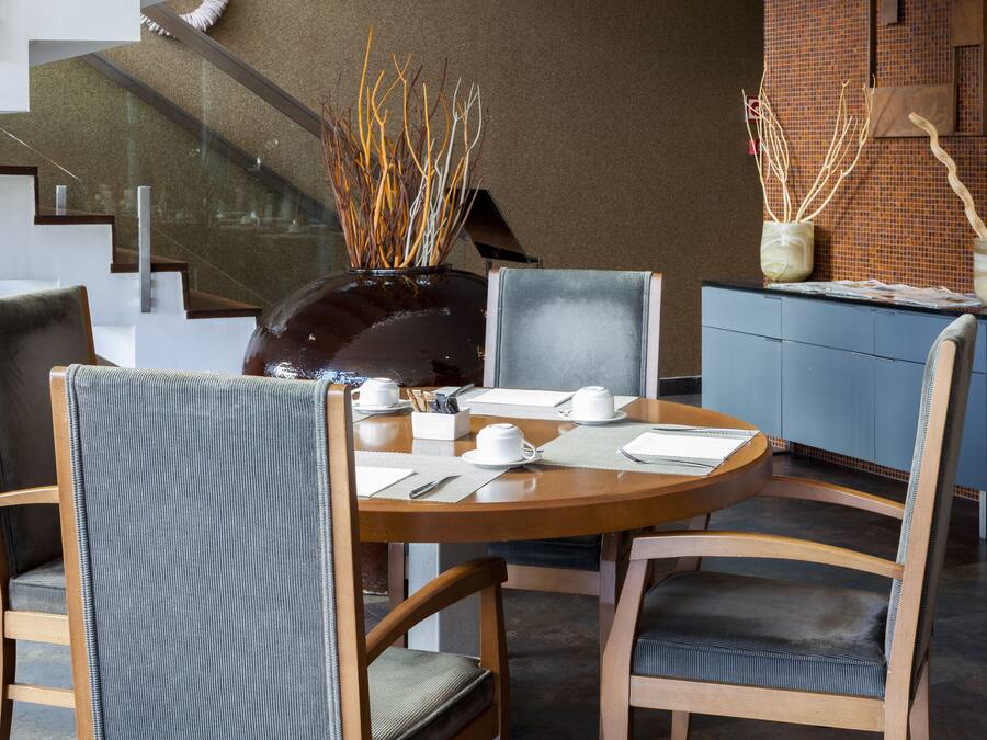 A dining area with a round table, chairs, and a vase with decorative branches.