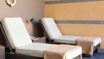 Two lounge chairs with cushions, a lamp, and a wall with a geometric pattern.