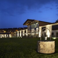 A modern building with a glass facade and a stone sculpture in the foreground.