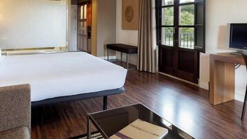 Hotelkamer met een groot bed, een bureau, een stoel, een televisie en een raam met gordijnen.