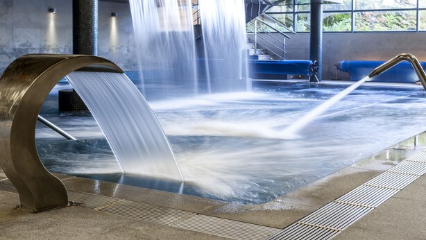 A water feature with a curved metal structure and a pool.
