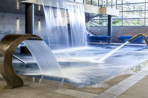 A water feature with a curved metal structure and a pool.