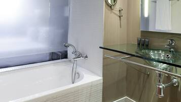 Ein modernes Badezimmer mit einem Glaskonstruktion-Waschbecken, einer großzügigen Badewanne und einem Spiegel über dem Waschbecken.