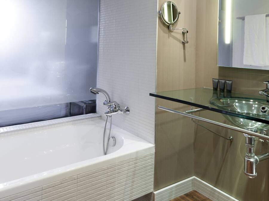 Ein modernes Badezimmer mit einem Glaskonstruktion-Waschbecken, einer großzügigen Badewanne und einem Spiegel über dem Waschbecken.