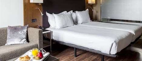 Una habitación de hotel con una cama grande, un sofá, una mesita de noche con una bandeja de desayuno y un espejo amplio.