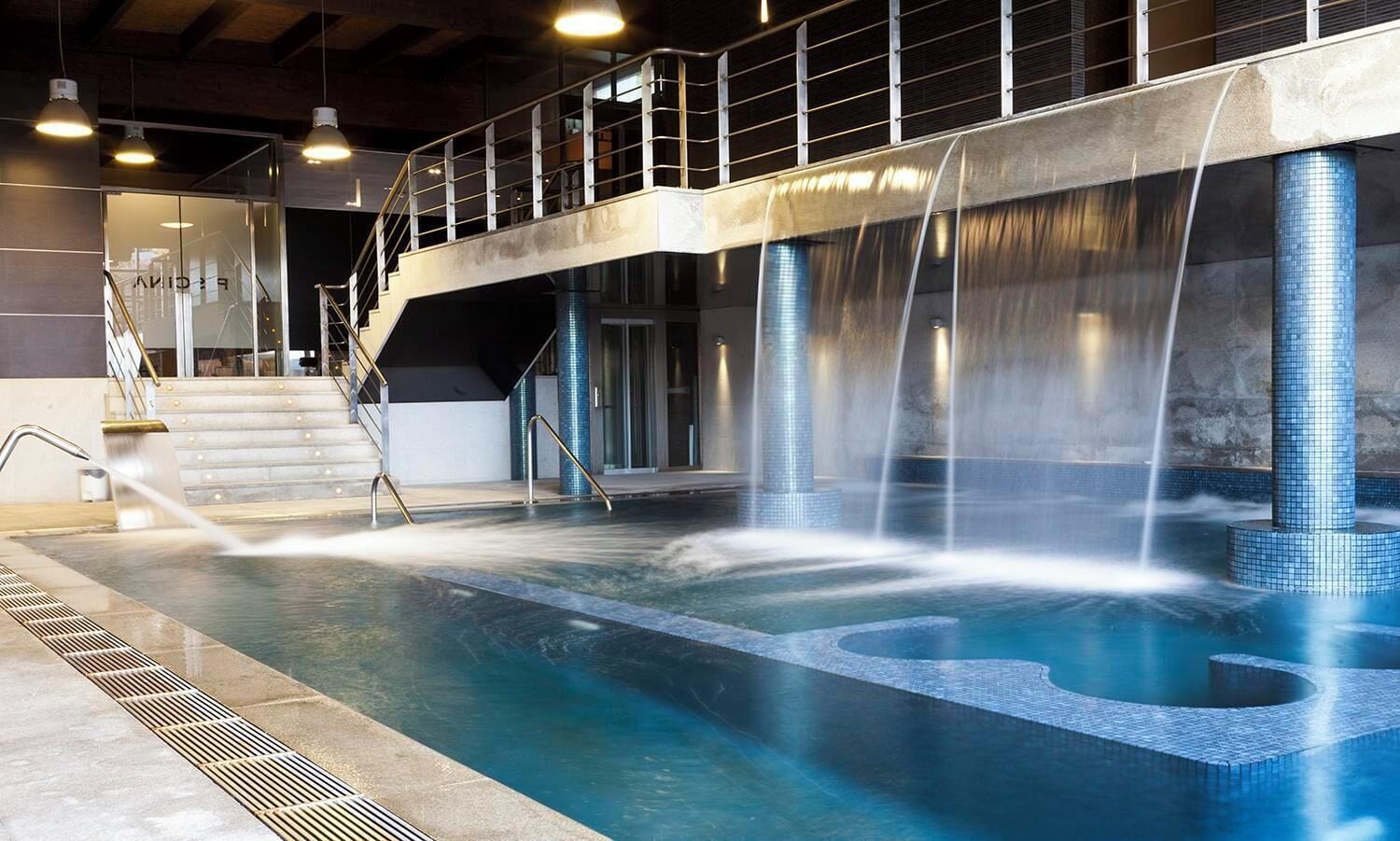 A swimming pool with multiple water features, including waterfalls and a central fountain.
