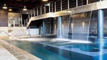 A swimming pool with multiple water features, including waterfalls and a central fountain.