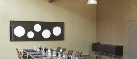 A conference room with a long table, chairs, and a large screen.