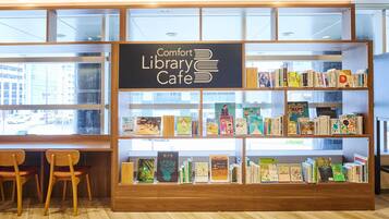 A library cafe with bookshelves, wooden chairs, and a sign reading 'Comfort Library Cafe.'