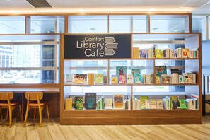 A library cafe with bookshelves, wooden chairs, and a sign reading 'Comfort Library Cafe.' - Comfort Hotel Sendai East (Sendai)