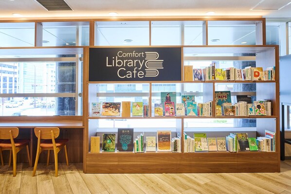 A library cafe with bookshelves, wooden chairs, and a sign reading 'Comfort Library Cafe.'