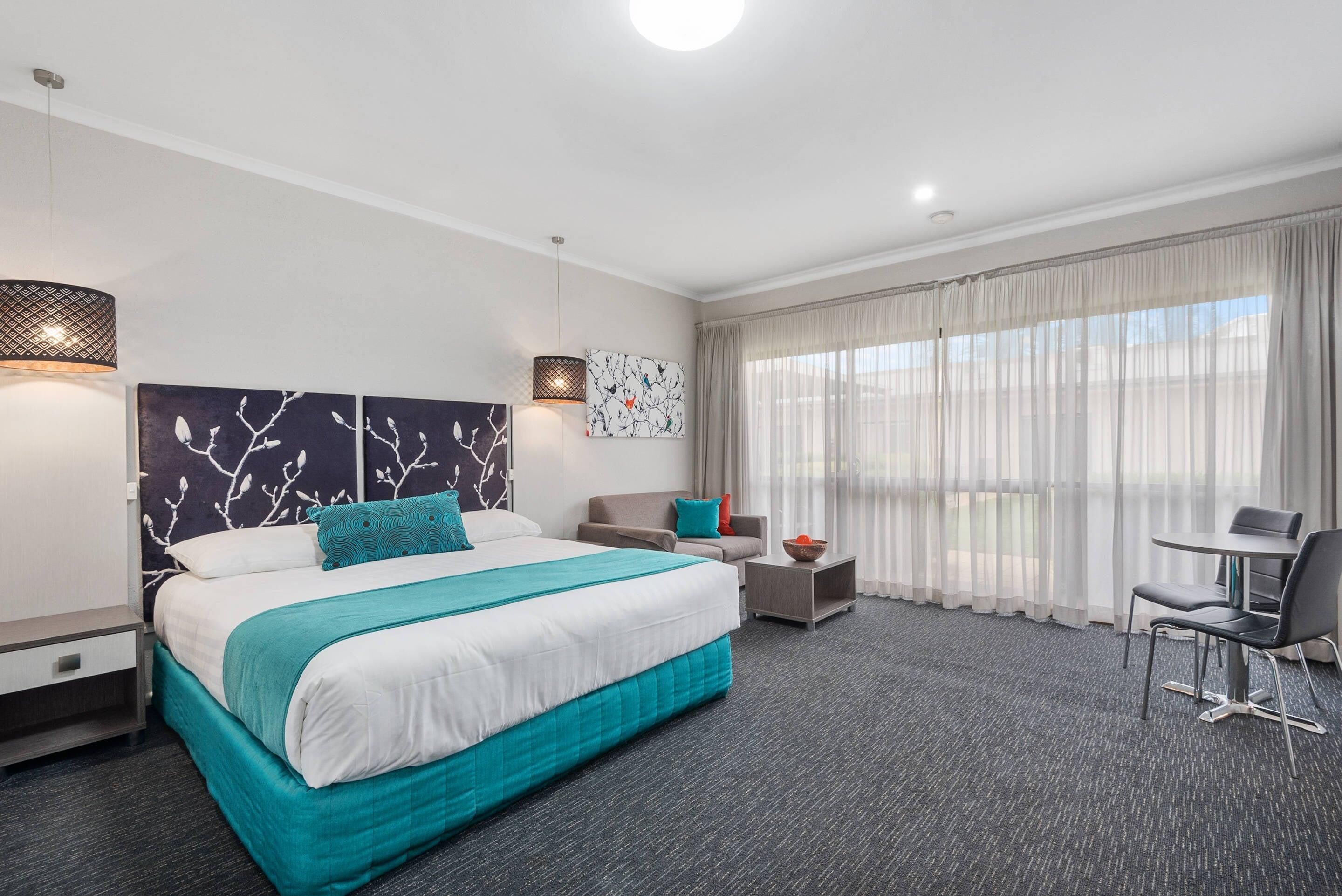 Une chambre d’hôtel avec un grand lit, un canapé, une petite table et une chaise.