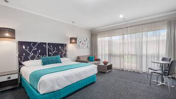 Ein Hotelzimmer mit einem großen Bett, einer Couch, einem kleinen Tisch und einem Sessel.