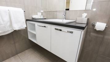 A modern bathroom with a white vanity, a sink, and a mirror.