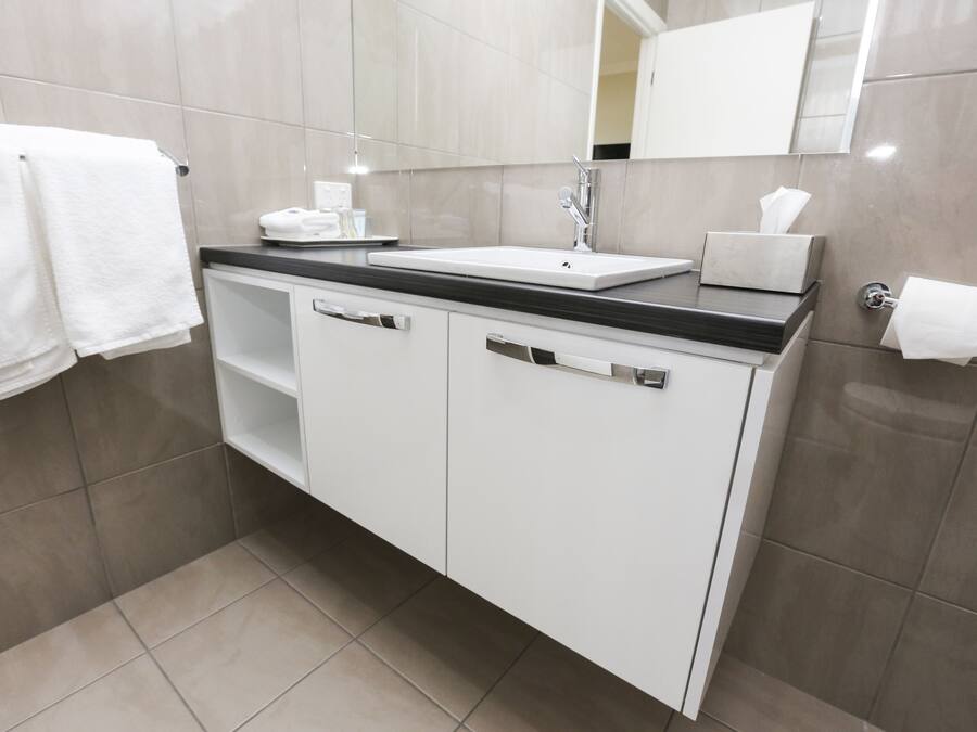 A modern bathroom with a white vanity, a sink, and a mirror.