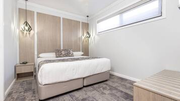 Un dormitorio con cama, mesitas de noche, ventilador de techo y ventana.