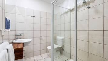 A modern bathroom with a glass-enclosed shower, a sink, and a toilet.