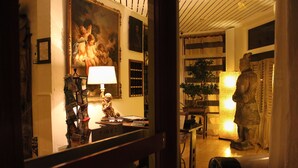 Un vestíbulo de hotel con un espejo grande que refleja un cuadro, una estatua y una lámpara.