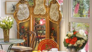 Un comedor con una mesa dispuesta para dos personas, rodeada de sillas y un separador decorativo con obras de arte.