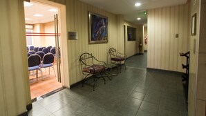 Un pasillo de hotel con una zona de estar, una obra de arte enmarcada en la pared y un extintor.