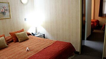 A hotel room with a bed, a nightstand, a lamp, and a painting on the wall.
