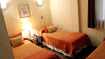 A hotel room with two beds, a nightstand, a lamp, and a framed picture on the wall.