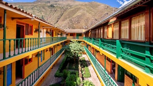 Un patio central con jardín, rodeado de edificios amarillos con barandillas verdes y puertas rojas.
