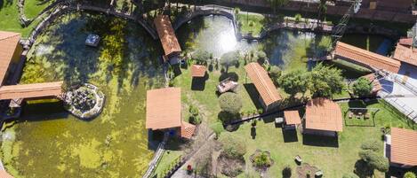 Vista aérea de un barrio residencial con varias casas, un estanque central y un puente.