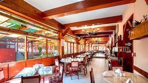 Un restaurante con vigas de madera, vidrieras de colores y mesas dispuestas para comer.
