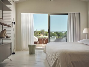 A hotel room with a bed, a desk, a chair, and a balcony with a view. - Ekies All Senses Resort, a Member of Design Hotels (Sithonia)