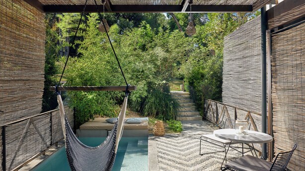 A hammock chair, a small pool, and a table with chairs in a covered outdoor area. - Ekies All Senses Resort, a Member of Design Hotels (Sithonia)