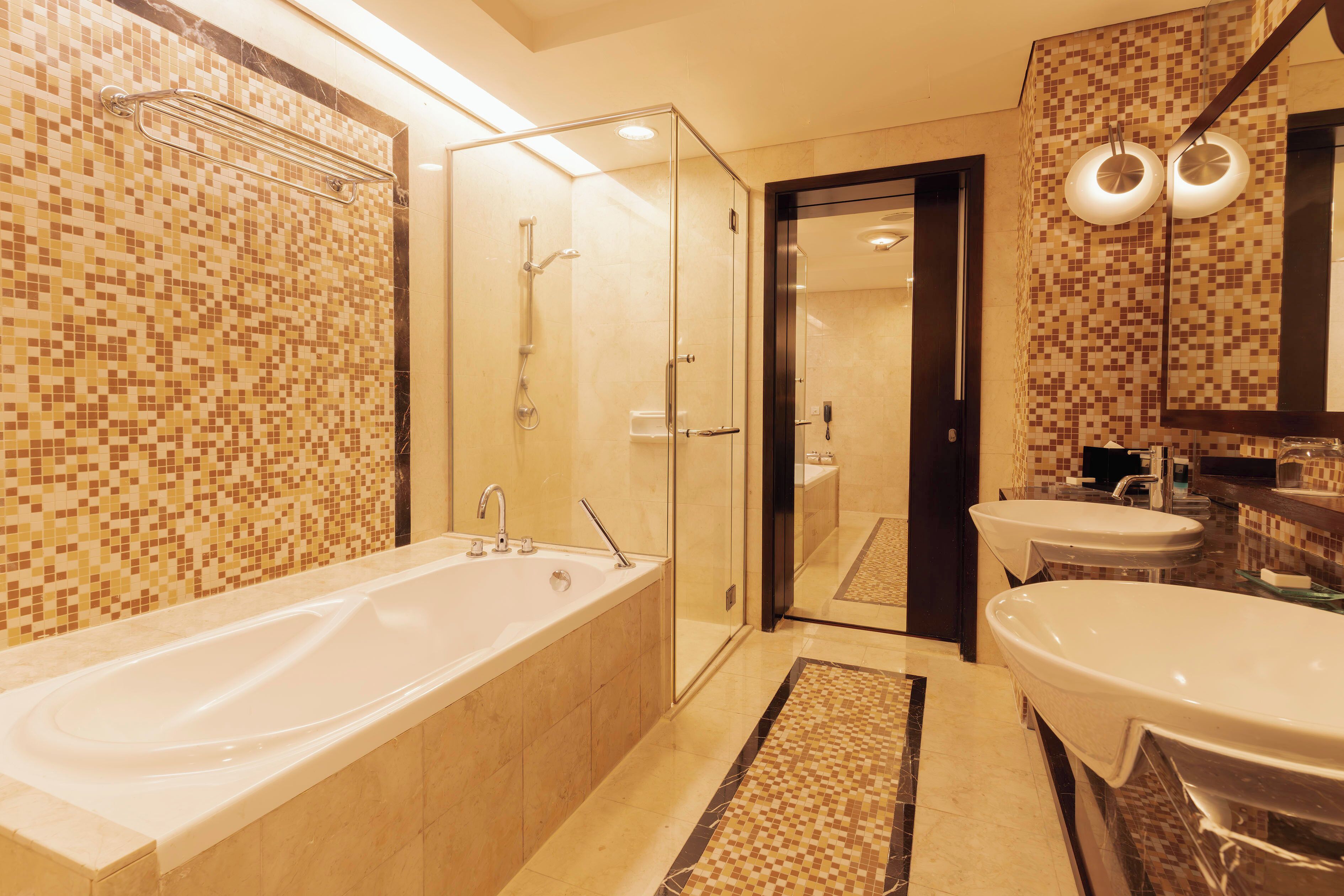 A modern bathroom with a large bathtub, two sinks, and a glass-enclosed shower area.