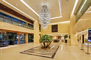 A spacious lobby with a large chandelier, a central floral arrangement, and a modern design.