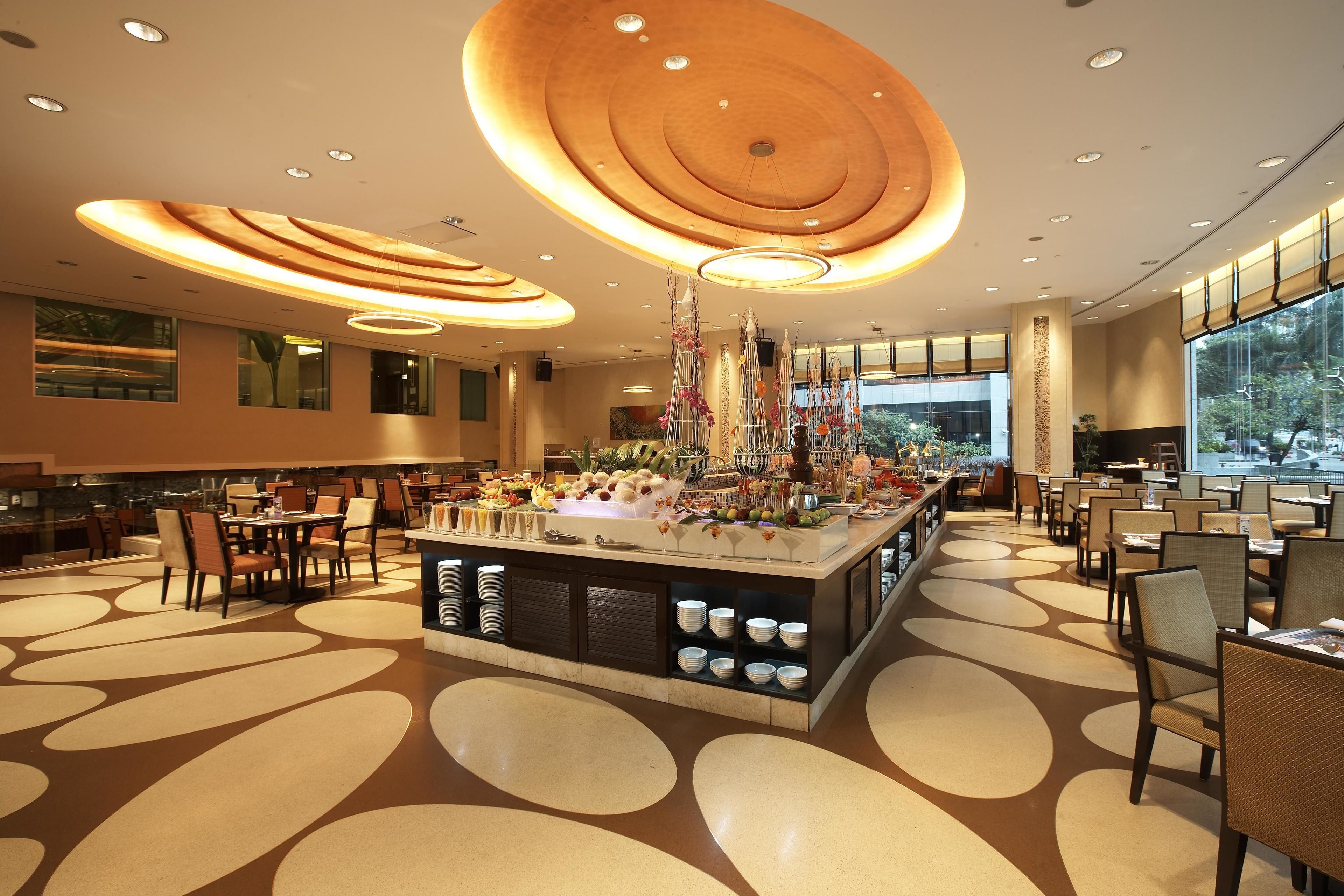 A spacious dining area with a central buffet, multiple seating arrangements, and a modern ceiling design.