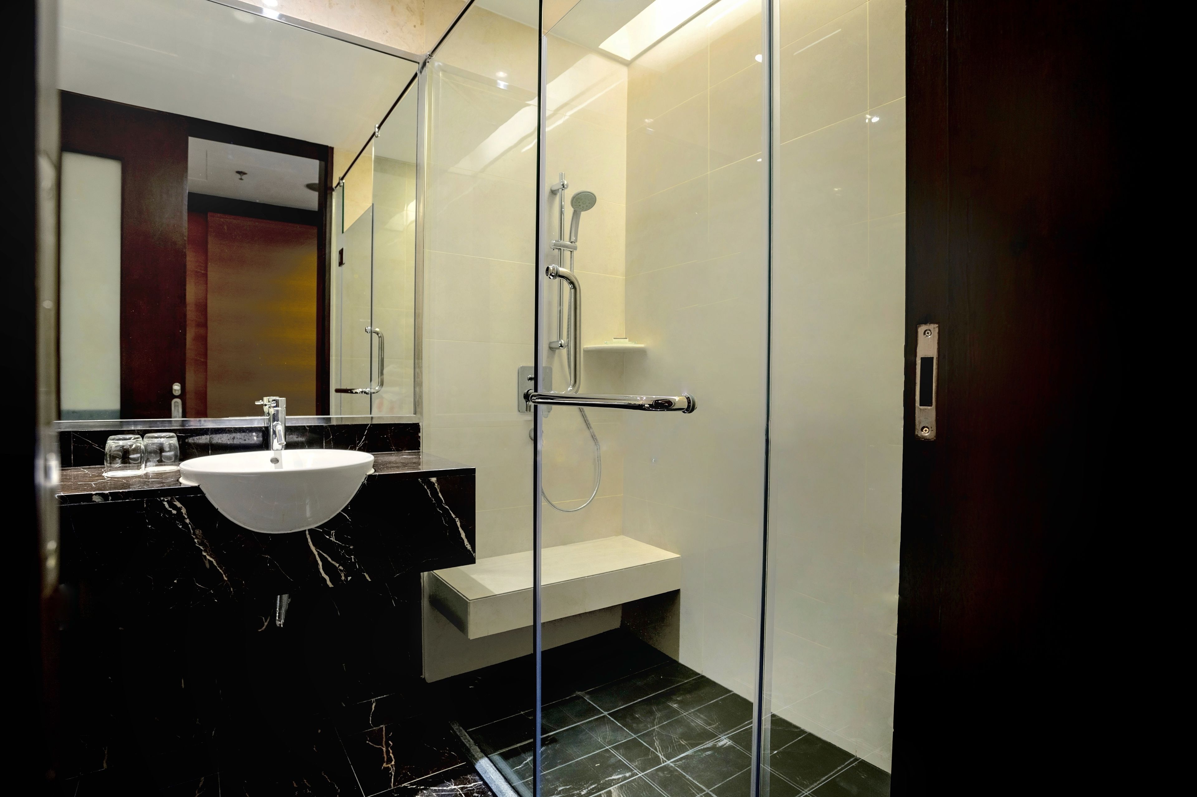 A modern bathroom with a glass-enclosed shower, a white sink, and a marble countertop.