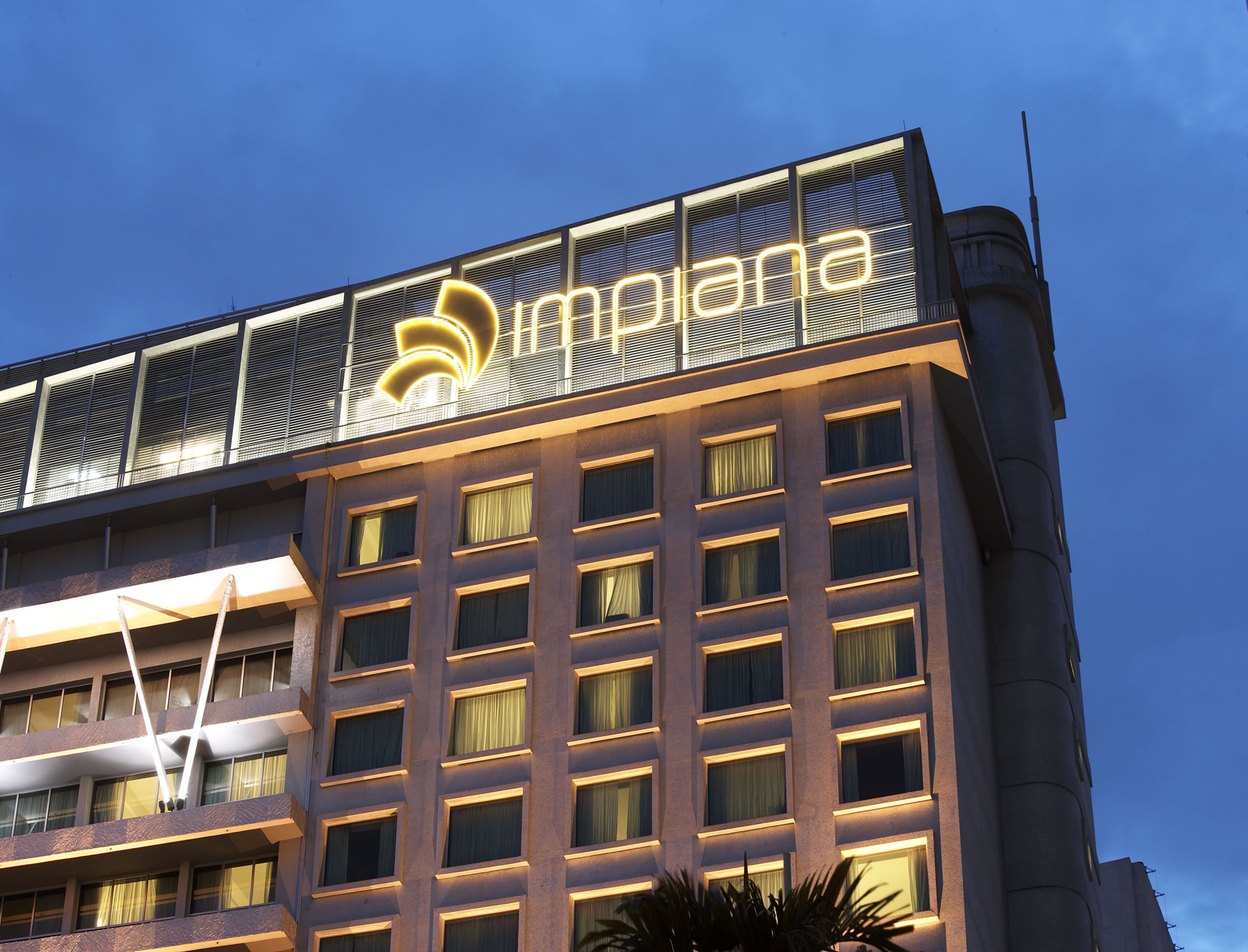 A hotel building with a prominent illuminated sign reading "Impana."