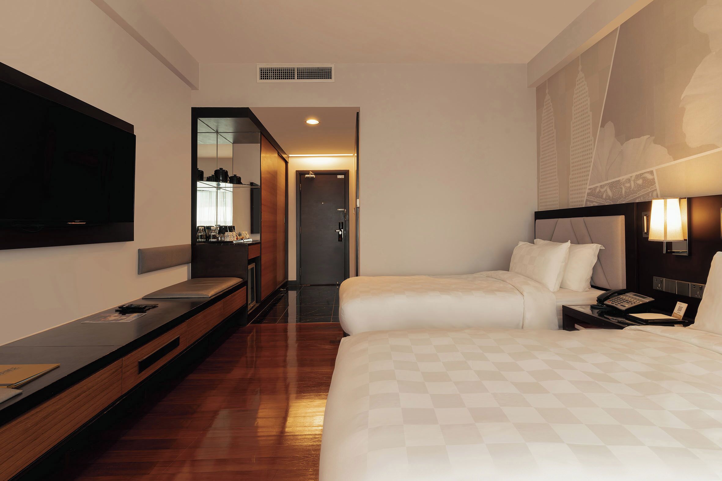 A hotel room with a large bed, a TV, a desk, and a bathroom visible through an open door.