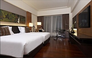 A hotel room with a large bed, a desk, and a television.