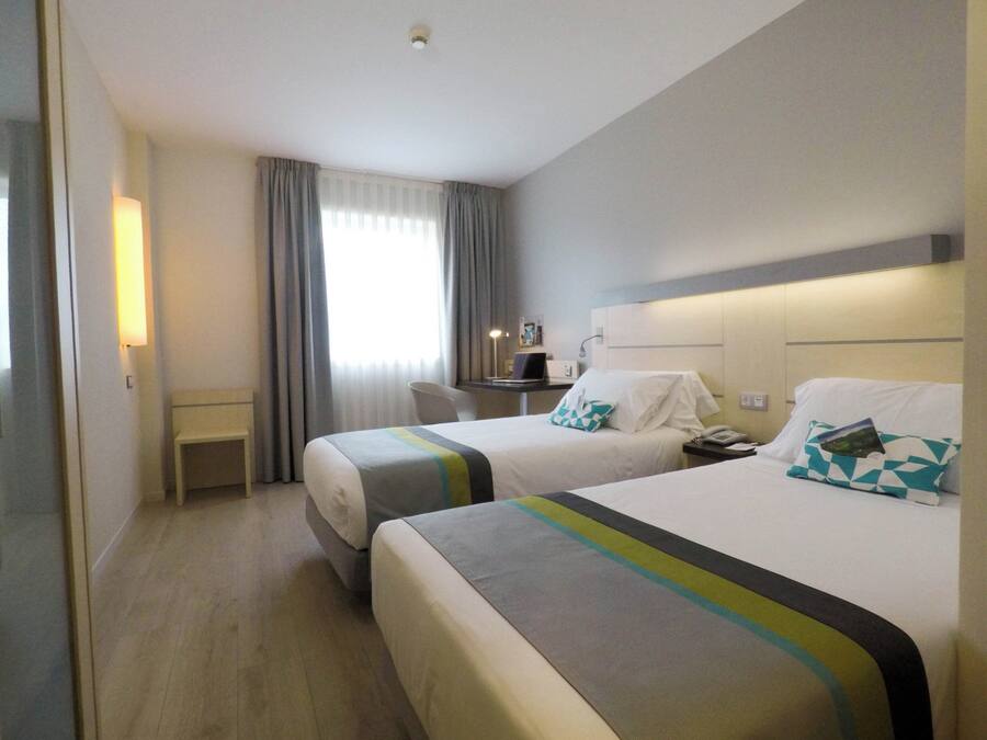 Una habitación de hotel con dos camas, un escritorio y una silla.