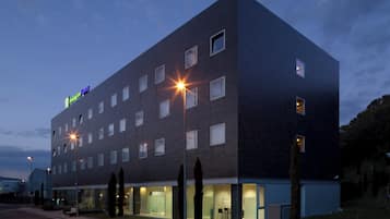 Un hôtel moderne, avec un bâtiment à la façade plate, de nombreuses fenêtres et une entrée bien visible, dotée de portes en verre.