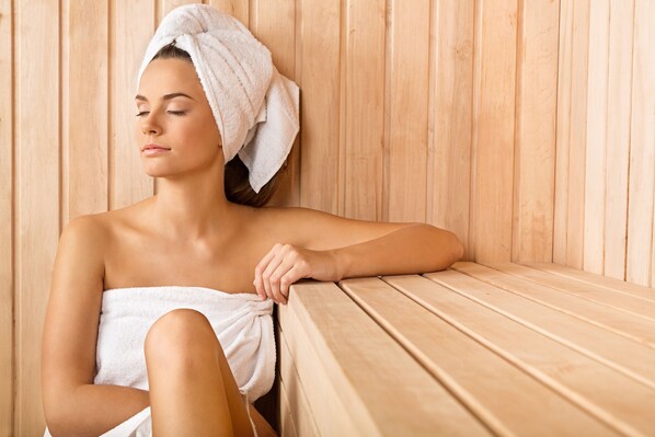 A person in a wooden sauna with a towel wrapped around their body. - Hotel Germania (Bregenz)