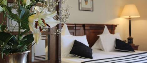 Una habitación de hotel con una cama, una lámpara de noche y una planta en maceta con flores.