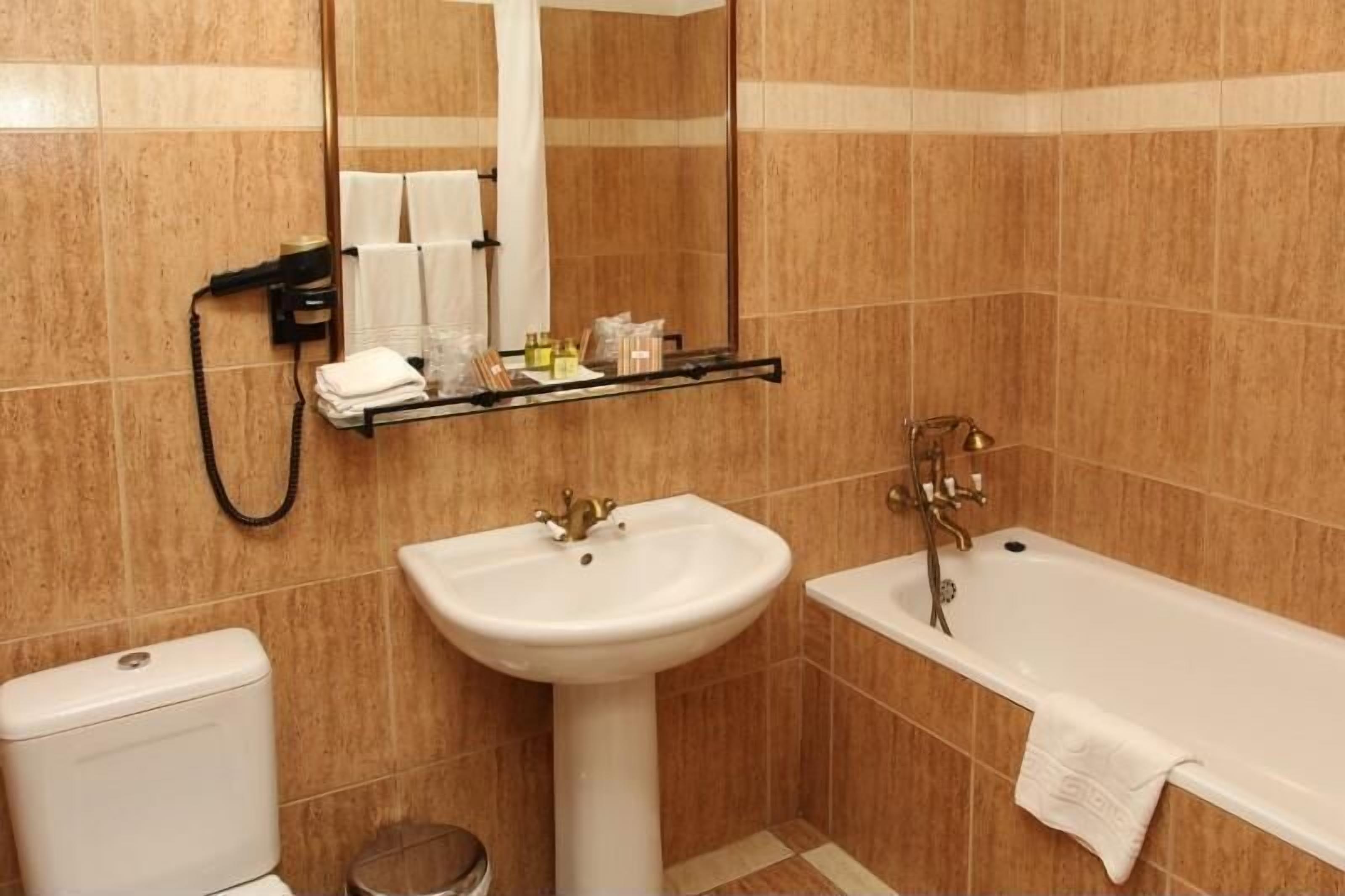 A bathroom with a white sink, a bathtub, and a toilet. There is a towel rack with towels and toiletries.