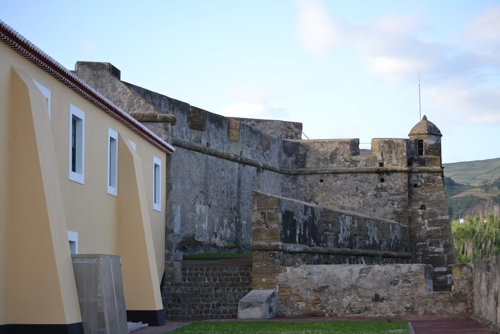 A historic stone wall adjacent to a modern building with a flat roof.
