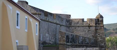A historic stone wall adjacent to a modern building with a flat roof.