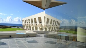 A modern building with a unique geometric design, large glass windows, and a view of the ocean. - Pousada de Angra do Heroismo - Forte Sao Sebastiao (Angra do Heroismo)